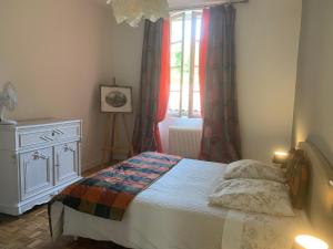 - une chambre avec un lit, une commode et une fenêtre dans l'établissement La Dépendance de Bazin, à Marmande