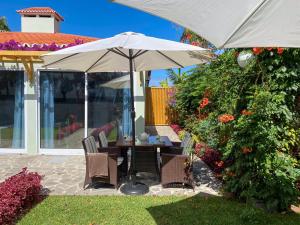 a table and chairs under an umbrella in a yard at Terra Vivaz - Ribeira Cottage in Ribeira Grande +81 photos