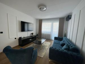 a living room with a blue couch and a tv at APARTMANI JERKOVIĆ - DUNAV 2 in Vukovar