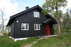 een zwart huis met een rode deur bij Granebo - Ustaoset in Ustaoset