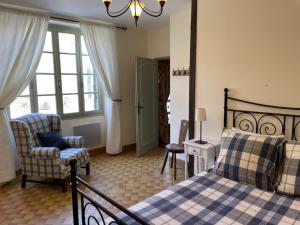 1 dormitorio con 1 cama, 1 silla y ventanas en Gites du Boussagou, en Marminiac