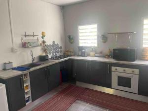 a kitchen with gray cabinets and a stove top oven at Maison de campagne in Kourou