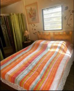 a bed with a colorful comforter in a bedroom at Maison de campagne in Kourou