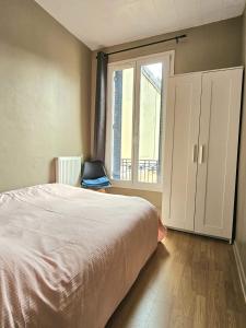een slaapkamer met een bed en een groot raam bij Charmante maison 2 chambres refait à neuf, à deux pas de Paris in Bagnolet