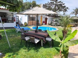 - une table avec un parasol à côté de la piscine dans l'établissement Montemar Apart Hotel - Playa Huanchaco, à Huanchaco
