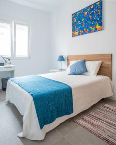 a bedroom with a large bed with a blue blanket at Habitacion a metros de la playa con cocina y WC compartida, terraza y zonas comunes in Valencia
