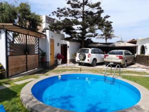 萬查科的住宿－Montemar Apart Hotel - Playa Huanchaco，一座房子的院子内的游泳池,有两辆车停放