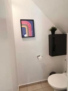 een badkamer met een toilet en een schilderij aan de muur bij Charmante maison 2 chambres refait à neuf, à deux pas de Paris in Bagnolet