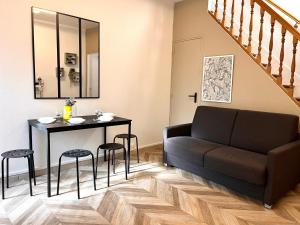 een woonkamer met een bank en een tafel met krukken bij Charmante maison 2 chambres refait à neuf, à deux pas de Paris in Bagnolet