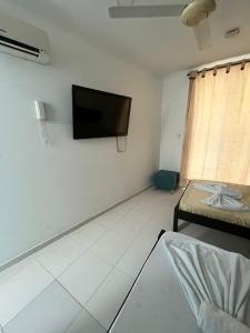 sala de estar con TV de pantalla plana en la pared en AW Hotel Rodadero Suites, en Santa Marta