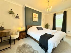 a bedroom with a bed and a desk and a chair at Chestnut Cottage in Dalmellington