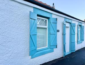 una fila de ventanas azules en un edificio blanco en Chestnut Cottage, en Dalmellington