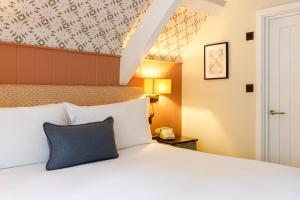 a bedroom with a large bed with a blue pillow at The Boot at Barnsley in Cirencester