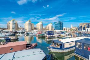 een groep boten aangemeerd in een haven met gebouwen bij Luxurious houseboat near Canary Wharf in London in Londen