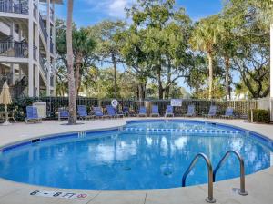 uma grande piscina com cadeiras e árvores em Seaside Villa 251 em Hilton Head Island