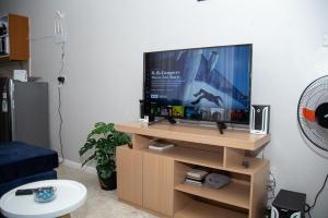 a living room with a flat screen tv on a wooden stand at 1 Bdr apartment with pool in Nairobi