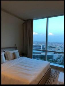 リヤドにあるLuxury Towers Apartment in Downtownのベッドと大きな窓が備わるホテルルームです。