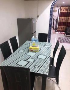 ein Tisch mit schwarzen Stühlen und ein Tisch mit Getränken darauf in der Unterkunft Anggerik homestay Klia Klia2 in Sepang