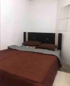 ein Schlafzimmer mit einem Bett mit einer braunen Decke und Kissen in der Unterkunft Anggerik homestay Klia Klia2 in Sepang