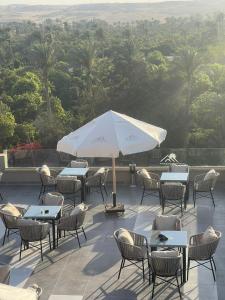 een patio met tafels en stoelen en een parasol bij Golden Pyramids Sunrise Hotel in Caïro