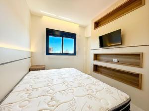 a bedroom with a bed and a flat screen tv at Apto NOVO, com piscina, 250m da praia in Bombinhas +22 photos