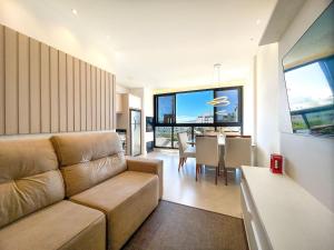 a living room with a couch and a dining room at Apto NOVO, com piscina, 250m da praia in Bombinhas