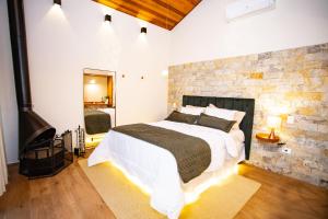 um quarto com uma cama grande e uma parede de tijolos em Chalés Quinta da Boa Vista em São Bento do Sapucaí