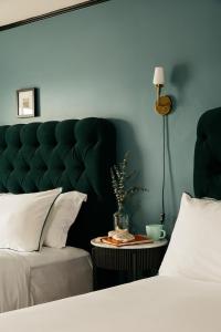 a bedroom with a green tufted headboard and a table at Hotel Emeline in Charleston