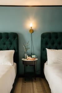 a room with two beds and a table with a lamp at Hotel Emeline in Charleston