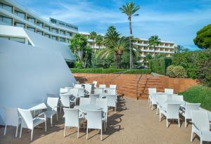 une rangée de tables et de chaises blanches devant un hôtel dans l'établissement Exagon Park, à Can Picafort