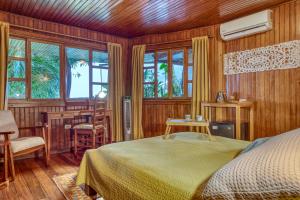 a bedroom with a bed and wooden walls and windows at Hotel Amor de Mar in Montezuma