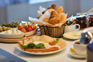 a table with plates of food and a basket of bread at Sleepinn Gdansk Airport in Gdańsk-Rębiechowo