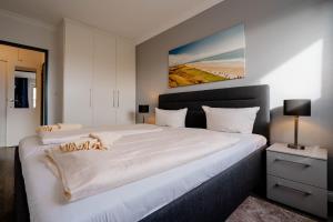 a bedroom with a large white bed with a painting on the wall at Sonnenidyll in Westerland
