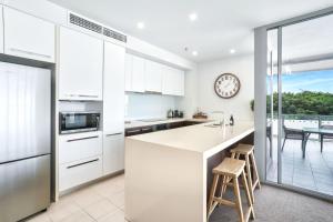 a kitchen with white cabinets and a clock on the wall at 11 Harbour Lights with Ocean Views in Cairns