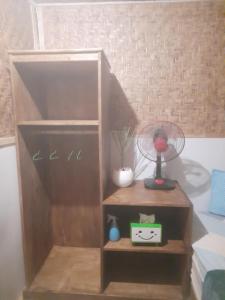 a book shelf with a fan and a lamp at Boneputeh Homestay in Taliwang