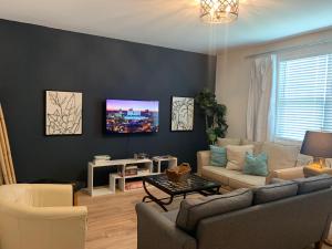 a living room with a couch and a tv on a wall at The Popular Pad in Downtown Raleigh, NC in Raleigh