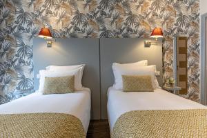two beds in a hotel room with two lamps at Splendid Hôtel in Paris