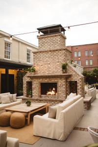 a patio with a brick fireplace with couches and a table at Hotel Emeline in Charleston