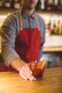 a man in a red apron holding a drink on a table at Hotel Emeline in Charleston