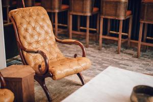 a brown leather chair sitting in a room with stool at Hotel Emeline in Charleston