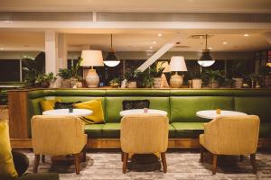 a green couch in a restaurant with tables and chairs at Hotel Emeline in Charleston