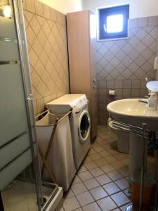 een badkamer met een wasmachine en een wastafel bij Appartamento panoramico Terranera in Terranera