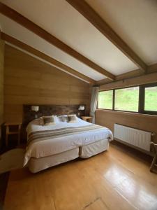 a bedroom with a large bed and a large window at Hotel Parque Quilquico in Quilquico