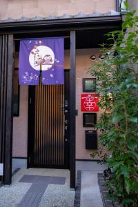 Una porta per un edificio con uno striscione sopra di 【Kyoto 幸】東寺まで１分、京都駅から15分！立地が便利な丸ごと貸し切る一軒家 a Kyoto