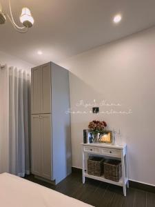 een slaapkamer met een witte muur met een tafel en een kast bij Mya's Home in Xuan An