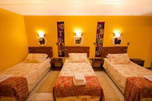 two beds in a room with yellow walls and mirrors at Hostal Kirckir in San Pedro de Atacama