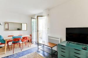 Superbe appartement grand et lumineux au 12ᵉ Paris في باريس: غرفة معيشة مع طاولة وكراسي وتلفزيون