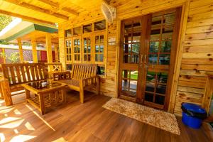 a wooden cabin with a porch with chairs and tables at Oxygen Palolem in Palolem