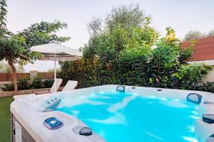 a hot tub in a yard with chairs and an umbrella at Pithea Luxury Living in Koroni
