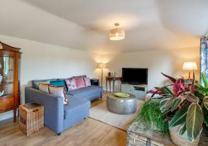 a living room with a blue couch and a tv at Blossom Cottage in Lakenheath